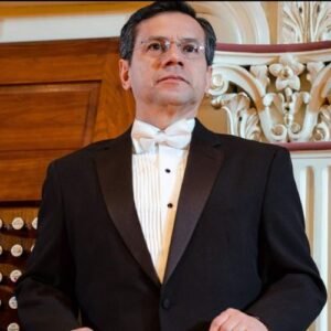 Luis Torres dressed formerly for concert with tux white shirt and bow tie. Organ in background